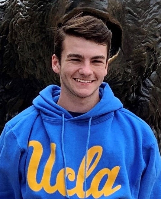 A person smiling in front of a statue

Description automatically generated